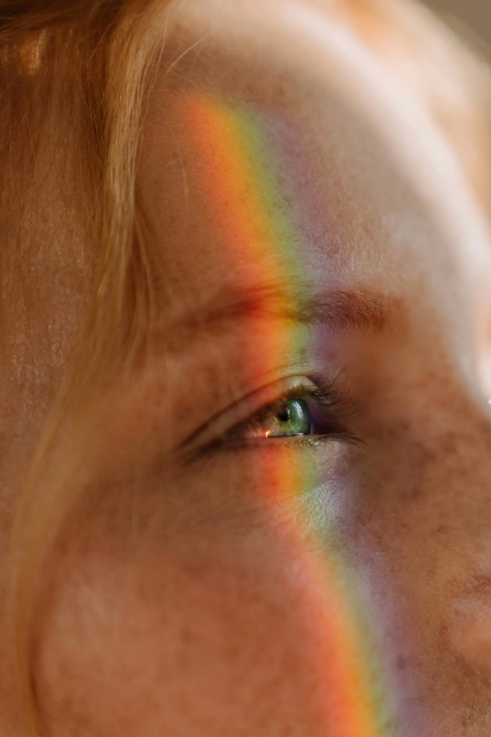 A close-up portrait with a prism of light across one eye