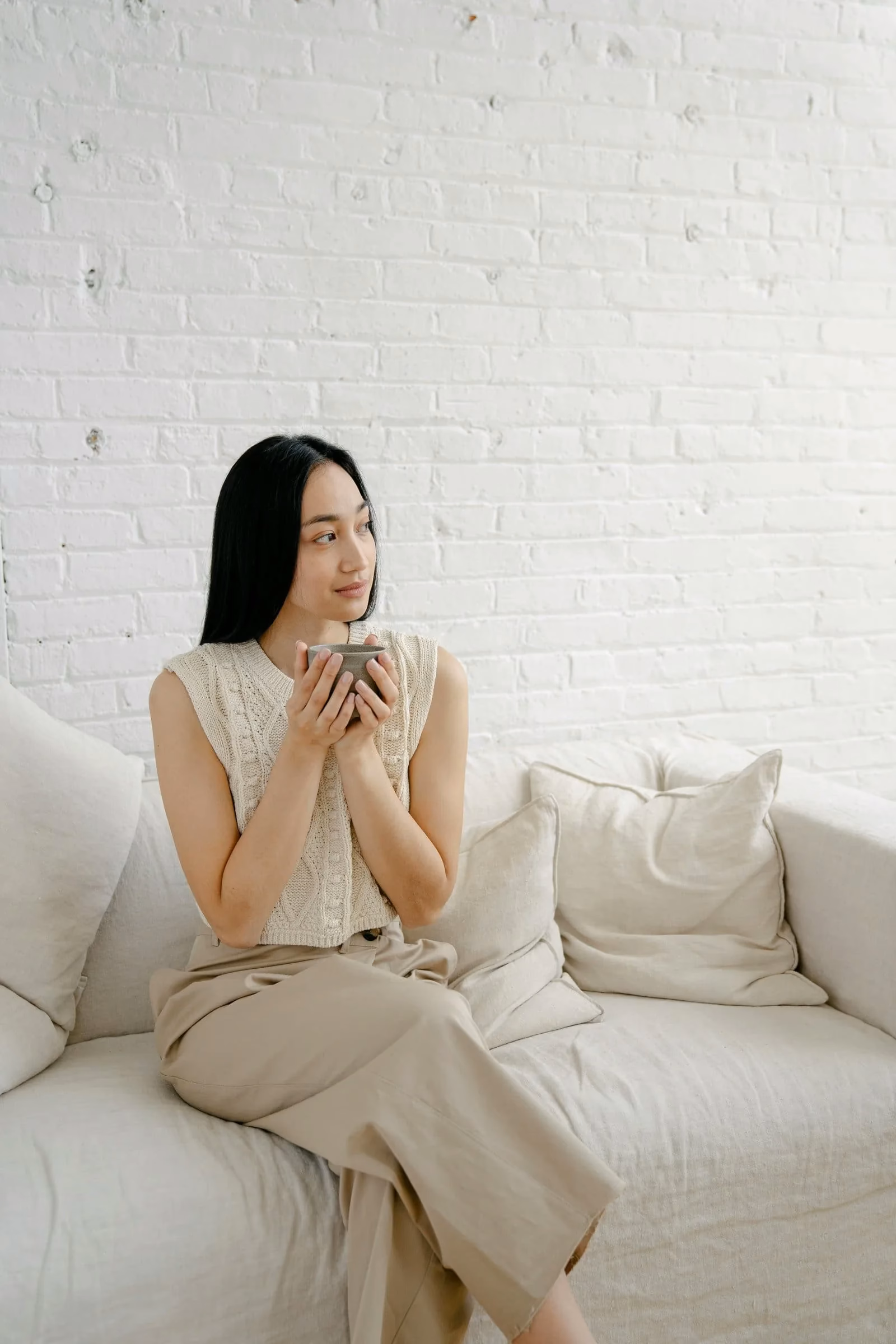 A woman seated quietly with a cup in a calm therapy-like setting