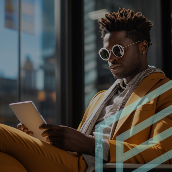 A person with short, curly hair wearing round sunglasses and a yellow suit jacket reads from a tablet while seated in a modern, sunlit room with large windows. Their serious expression matches the professional ambiance of their surroundings.