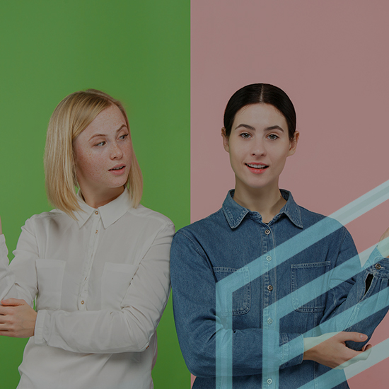 Two women stand side by side against a background split into green and pink halves. The woman on the left has blonde hair and wears a white shirt. The woman on the right has dark hair and wears a denim shirt. They are posing with relaxed expressions.