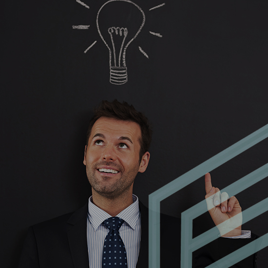 A man in a suit and tie stands against a dark background with a lightbulb drawing above his head. He is smiling and pointing upward toward the lightbulb, suggesting he has an idea.