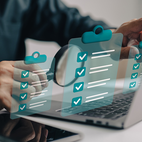 A person holds a magnifying glass while examining a laptop screen, which shows multiple floating checklists with check marks. A smartphone is placed on the table next to the laptop. The image conveys a sense of inspection, verification, or completion of tasks.