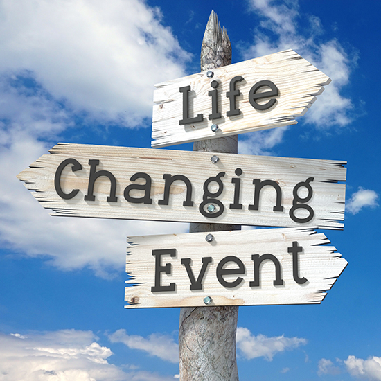 A weathered wooden signpost with three arrows points in different directions against a bright blue sky with scattered clouds. The signs read "Life," "Changing," and "Event." The text is bold and prominent against the rustic wood texture.